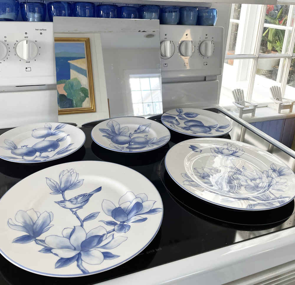 Alexandra's blue dishes on her stove, with a mirror reflecting the painting behind.