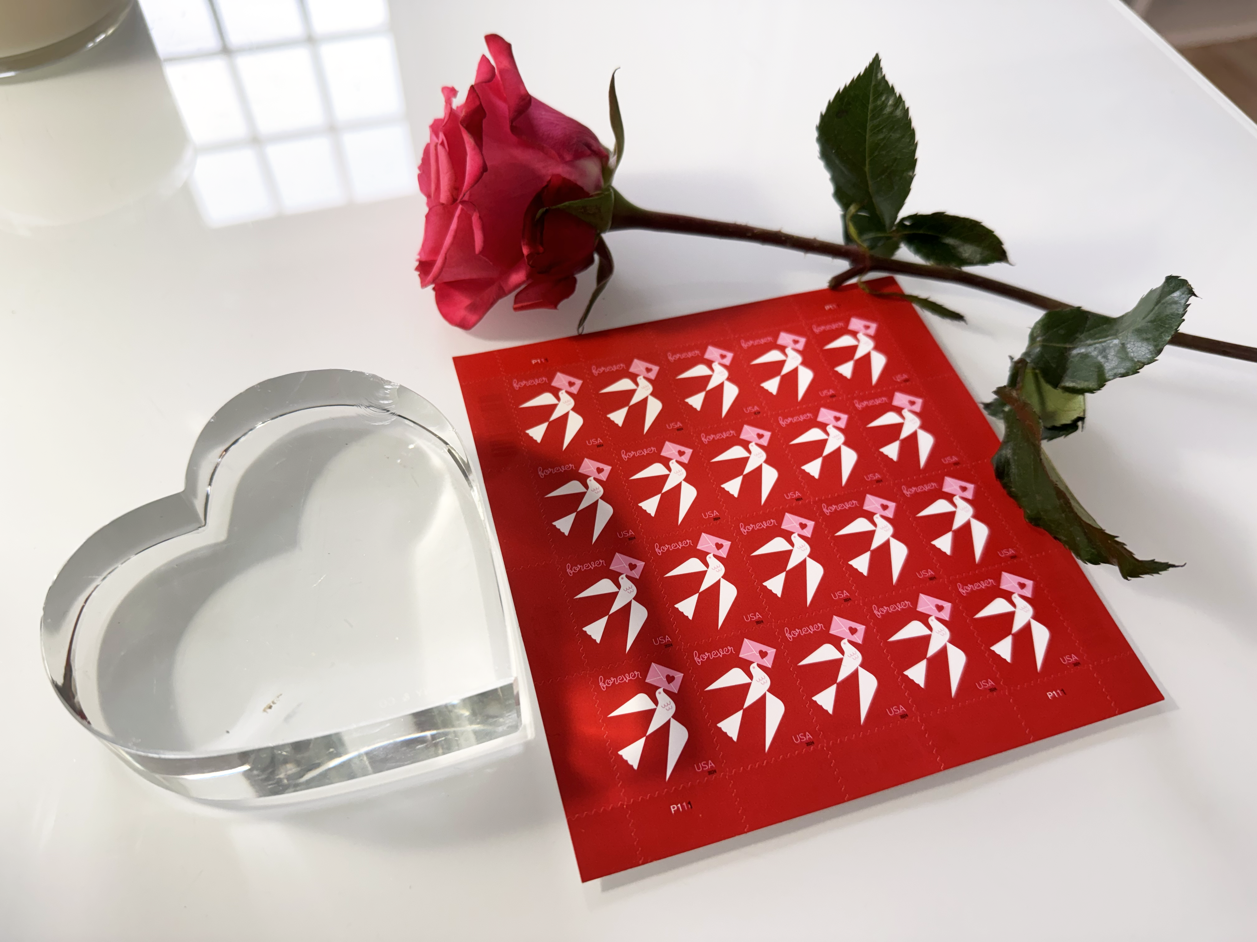 Red Forever stamps with a red rose and a heart-shaped paperweight