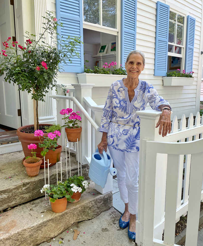 Alexandra watering plants in front of her house