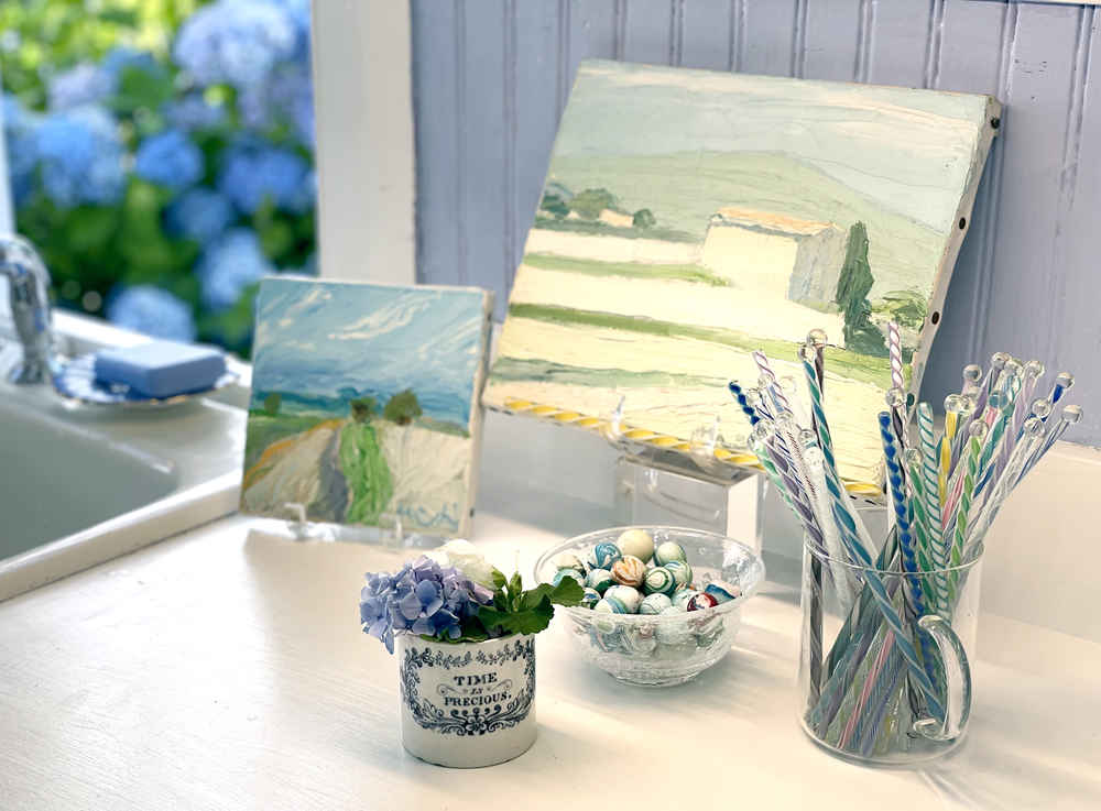 Flowers, paintings, swizzle sticks and marbles on display on the counter.