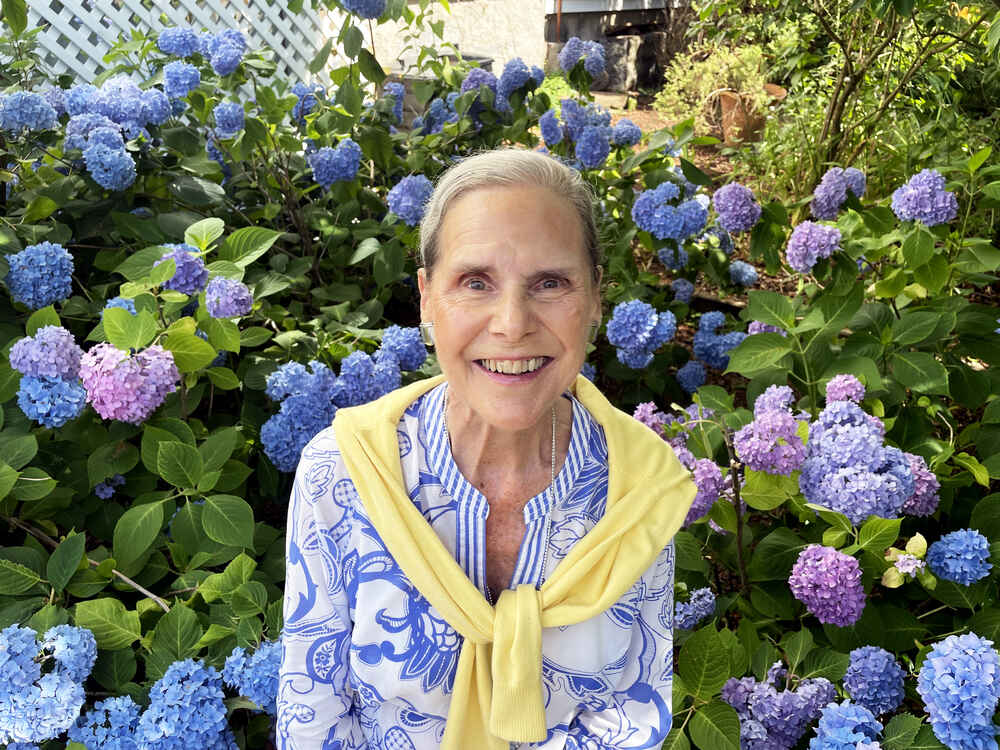 Alexandra sitting amid the hydrangeas in her garden.