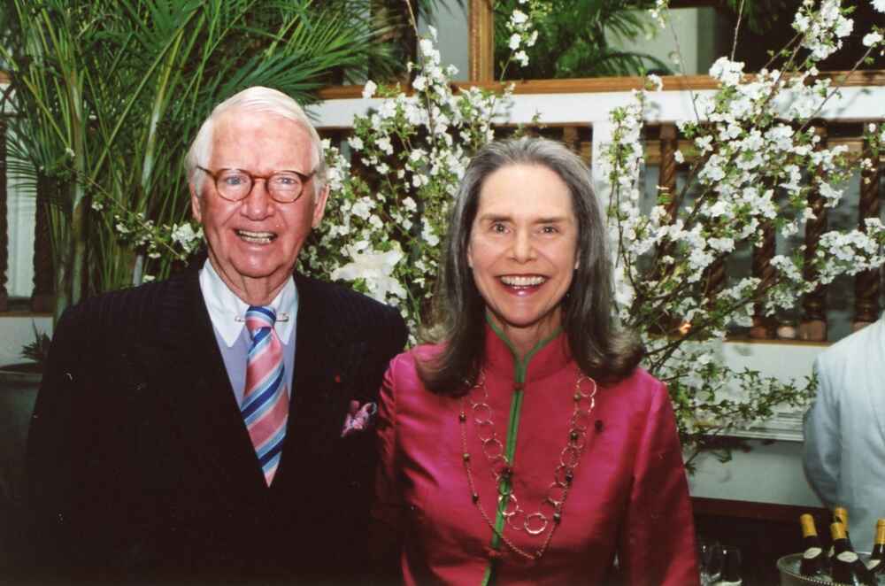 Peter and Alexandra in front of a spray of white flowers.