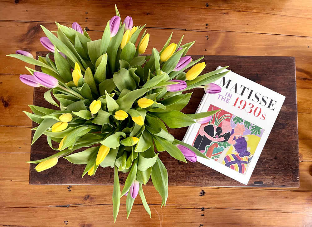 Yellow and purple tulips next to a book of Matisse art