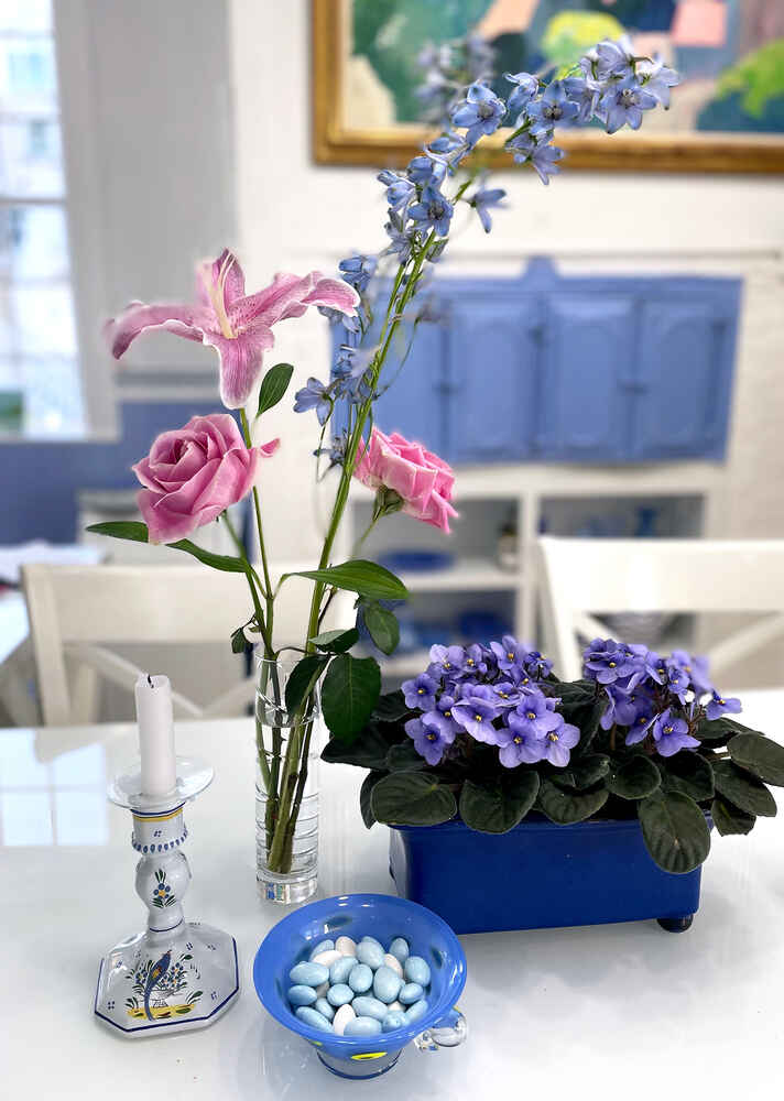 A vase of flowers, a potted plant and a bowl of jordan almonds on the kitchen table