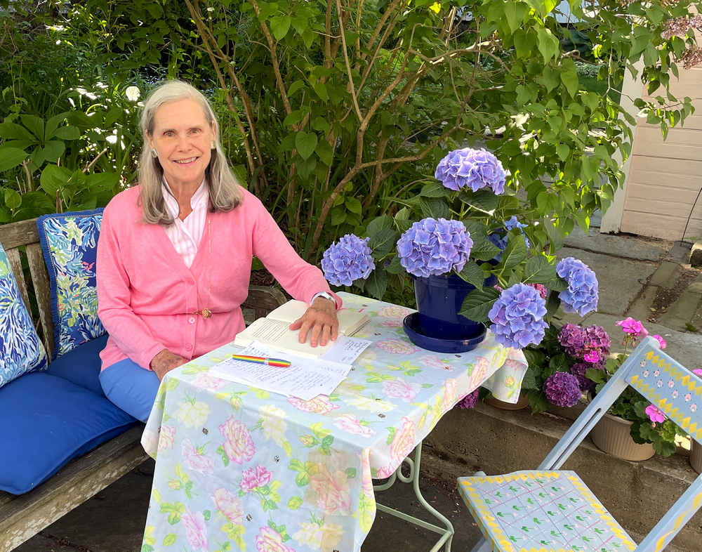 Alexandra at her writing desk in the garden, with hydrangea in a pot on the table