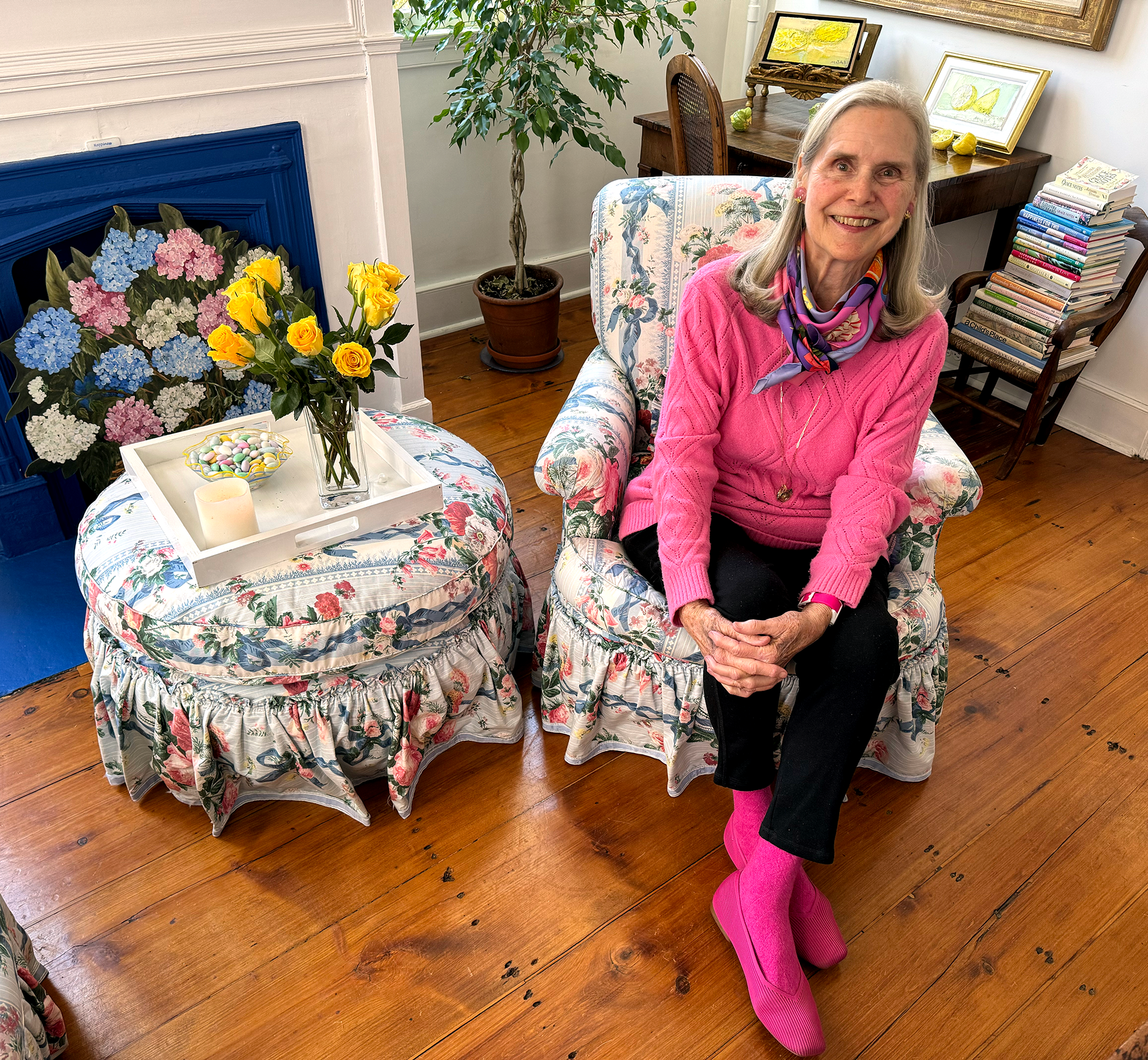 Alexandra in a chair wearing a bright pink sweater, bright pink socks and bright pink shoes